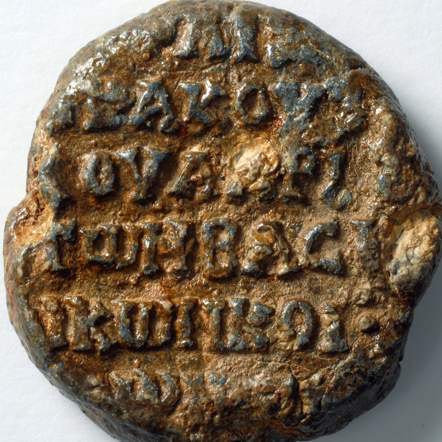 A Byzantine lead seal inscribed in Greek majuscule, naming a chartoularios of the imperial vestiarion